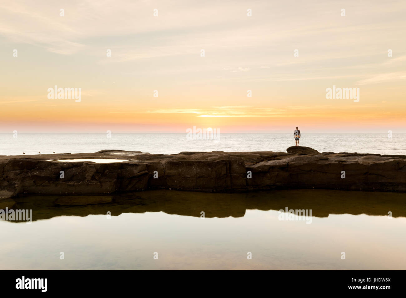 La silhouette d'une personne regarde le lever du soleil sur l'océan sur un littoral magnifique en Australie. Banque D'Images