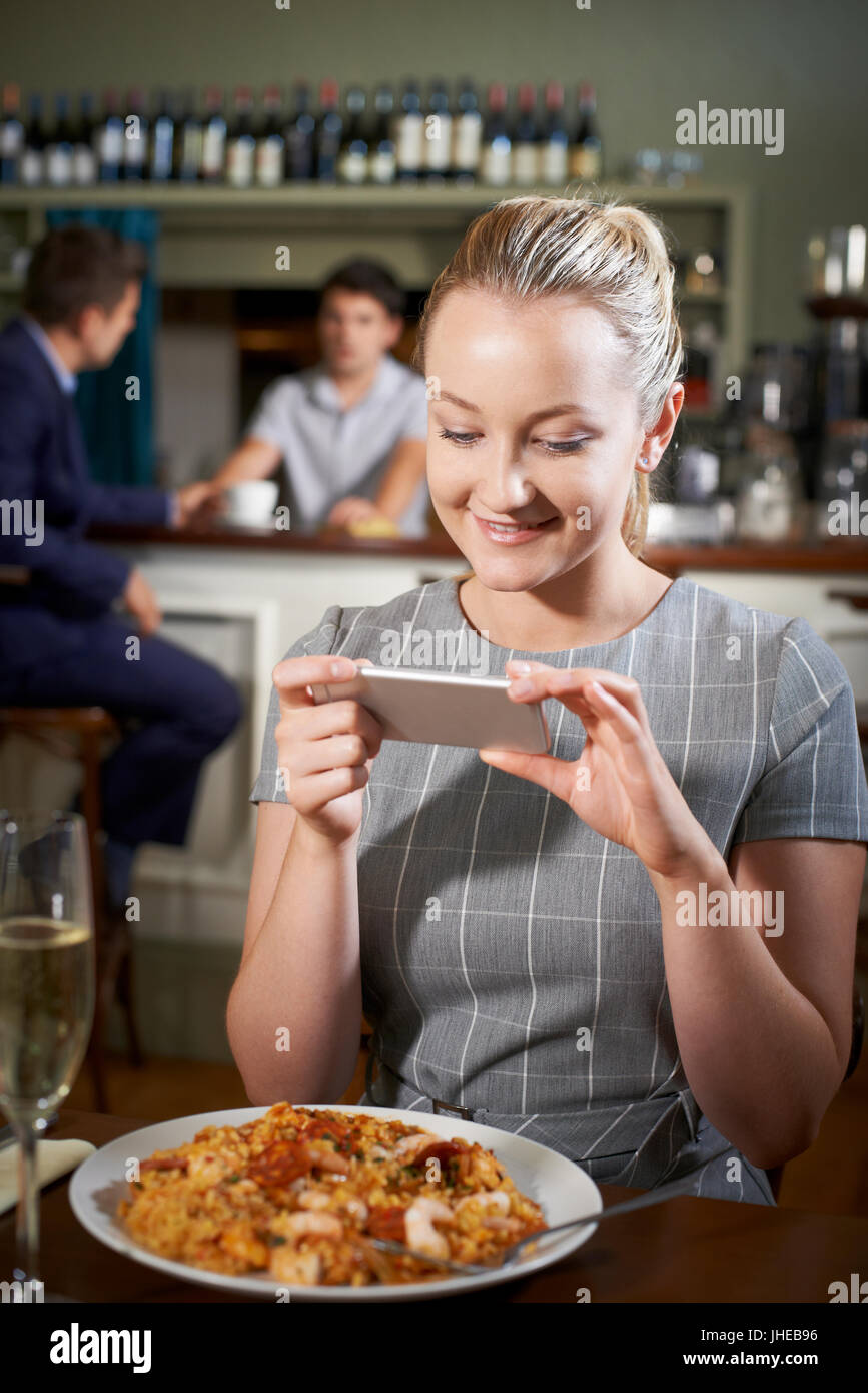 La prise de photo de Blogger nourriture Repas Restaurant On Mobile Phone Banque D'Images