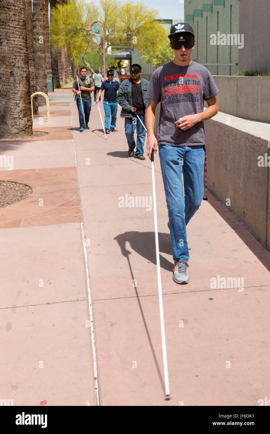 Phoenix, Arizona - aveugles et malvoyants, certains jeunes hommes portant des masques de sommeil, pratique la navigation dans les rues de la ville avec une canne blanche. Banque D'Images