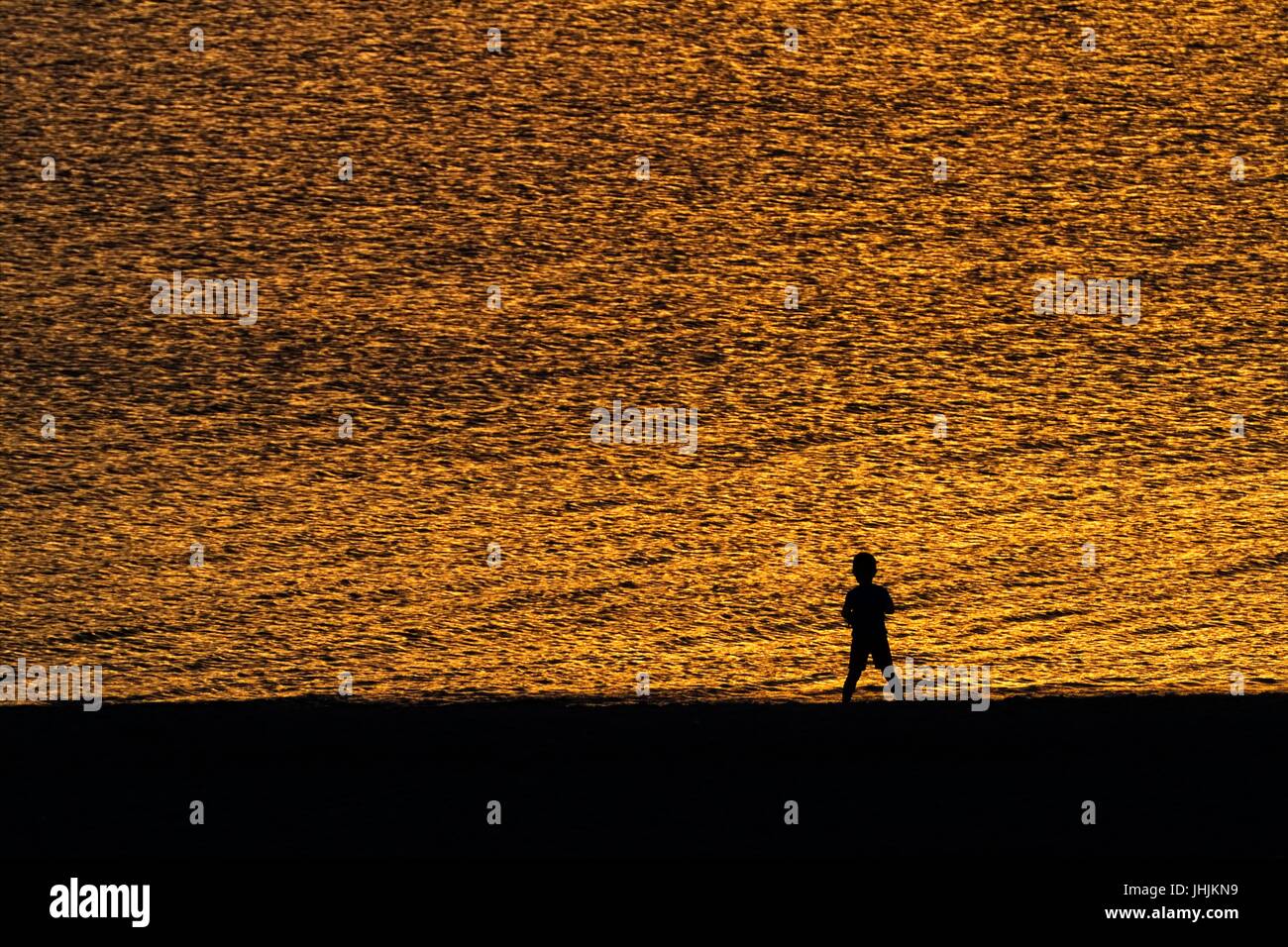 Coucher du soleil doré. Bord de mer. Silhouettes d'enfants. Banque D'Images