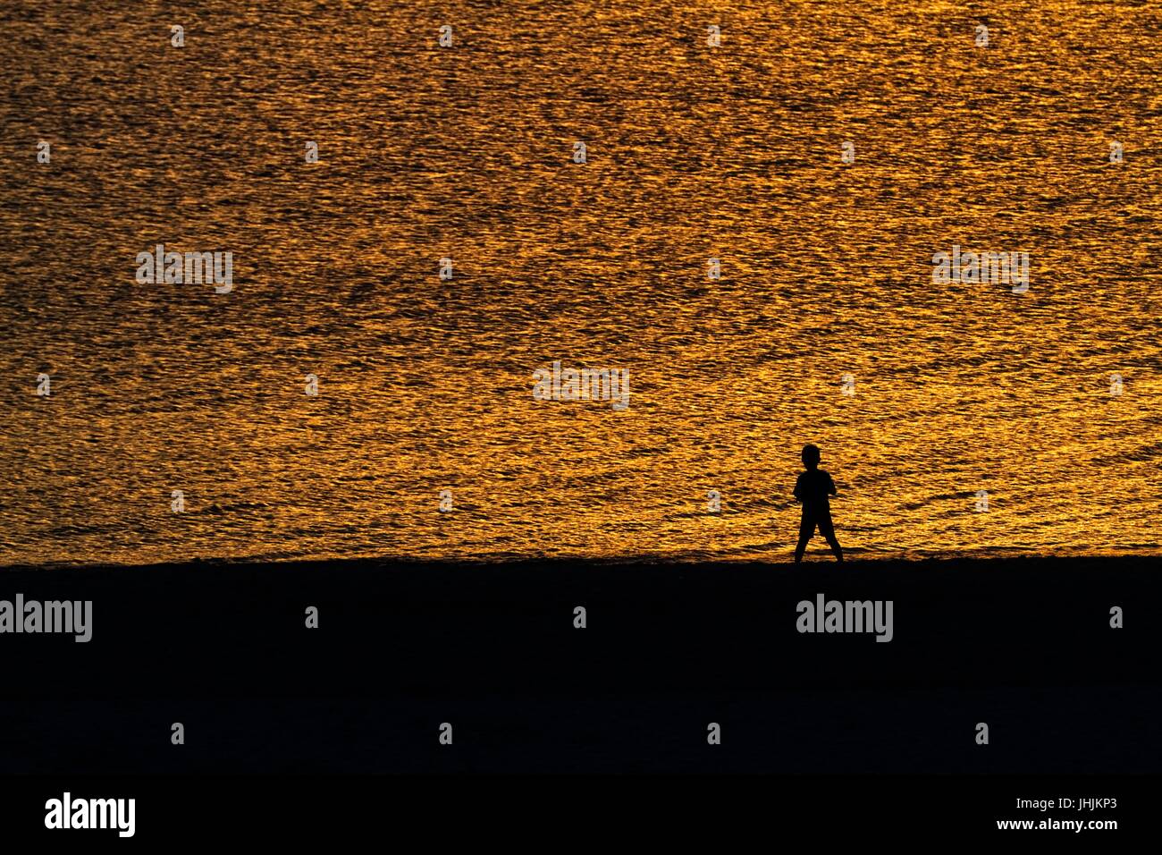 Coucher du soleil doré. Bord de mer. Silhouettes d'enfants. Banque D'Images