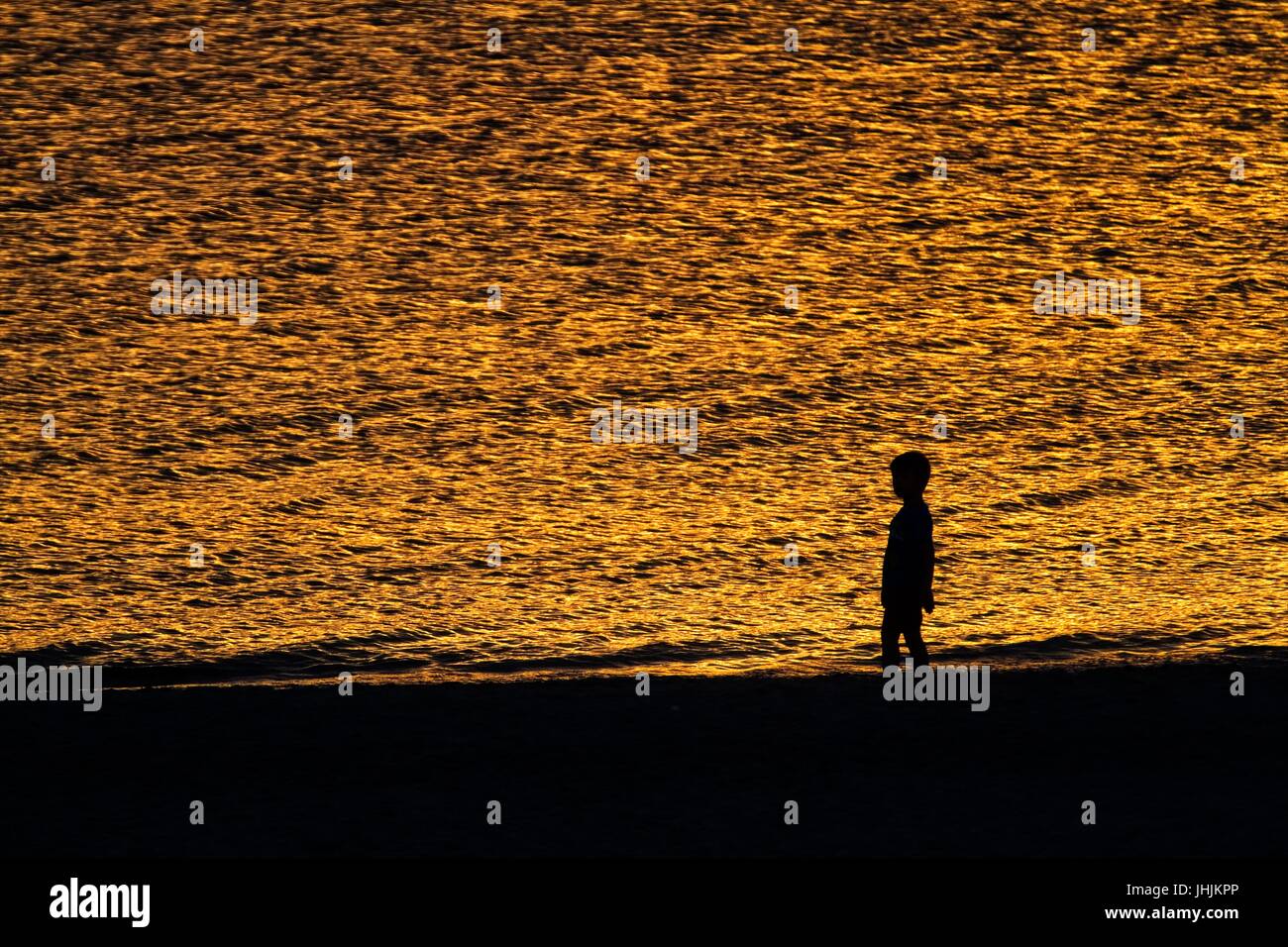 Coucher du soleil doré. Bord de mer. Silhouettes d'enfants. Banque D'Images