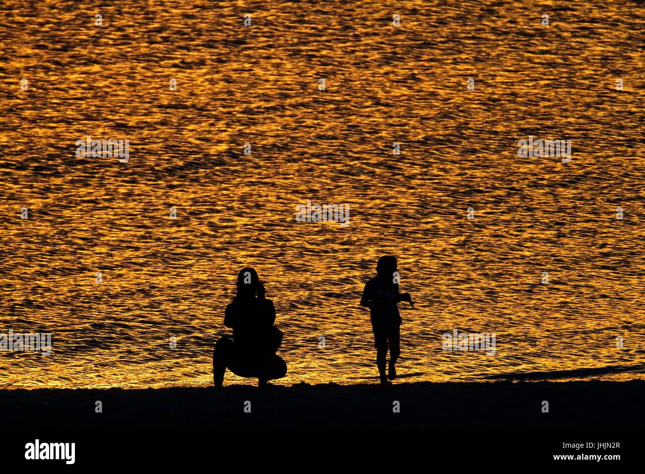 Coucher du soleil doré. Bord de mer. Silhouettes de la mère et l'enfant. Banque D'Images
