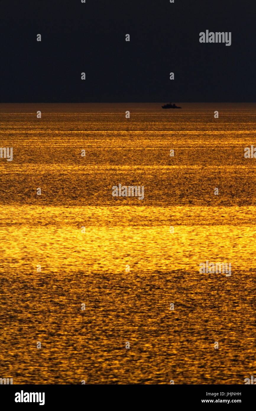 Coucher du soleil doré. Bord de mer. Silhouettes du cuirassé. Banque D'Images