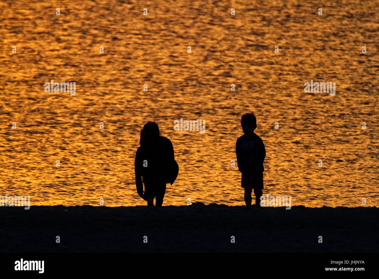 Coucher du soleil doré. Bord de mer. Silhouettes de la mère et l'enfant. Banque D'Images