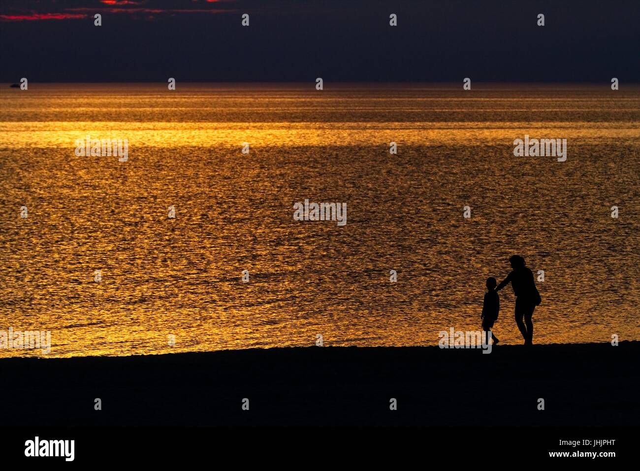 Coucher du soleil doré. Bord de mer. Silhouettes d'enfants. Banque D'Images