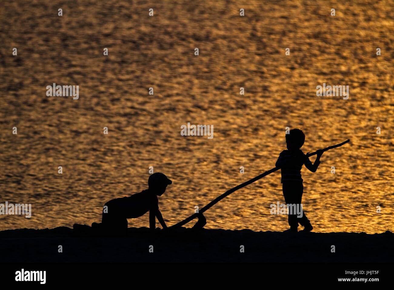 Coucher du soleil doré. Bord de mer. Silhouettes d'enfants. Banque D'Images