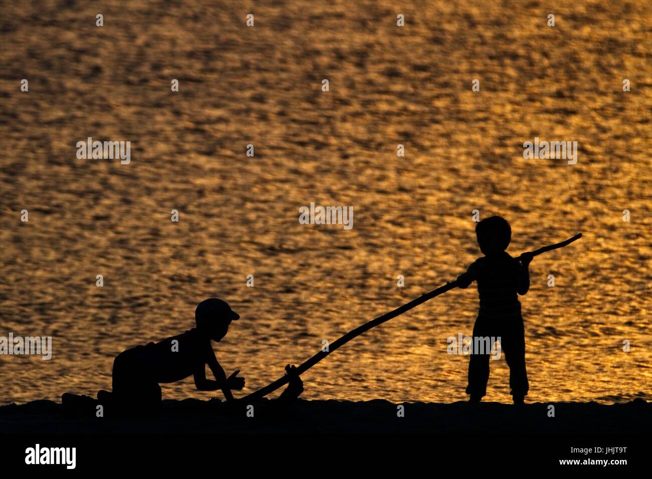 Coucher du soleil doré. Bord de mer. Silhouettes d'enfants. Banque D'Images