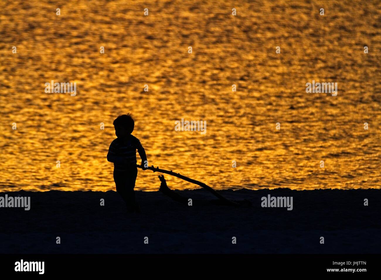 Coucher du soleil doré. Bord de mer. Silhouettes d'enfants. Banque D'Images