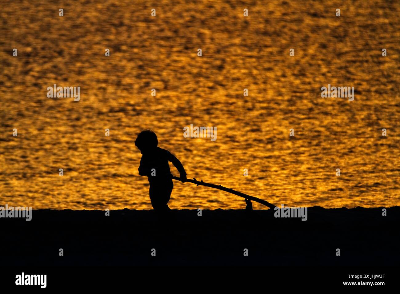 Coucher du soleil doré. Bord de mer. Silhouettes d'enfants. Banque D'Images
