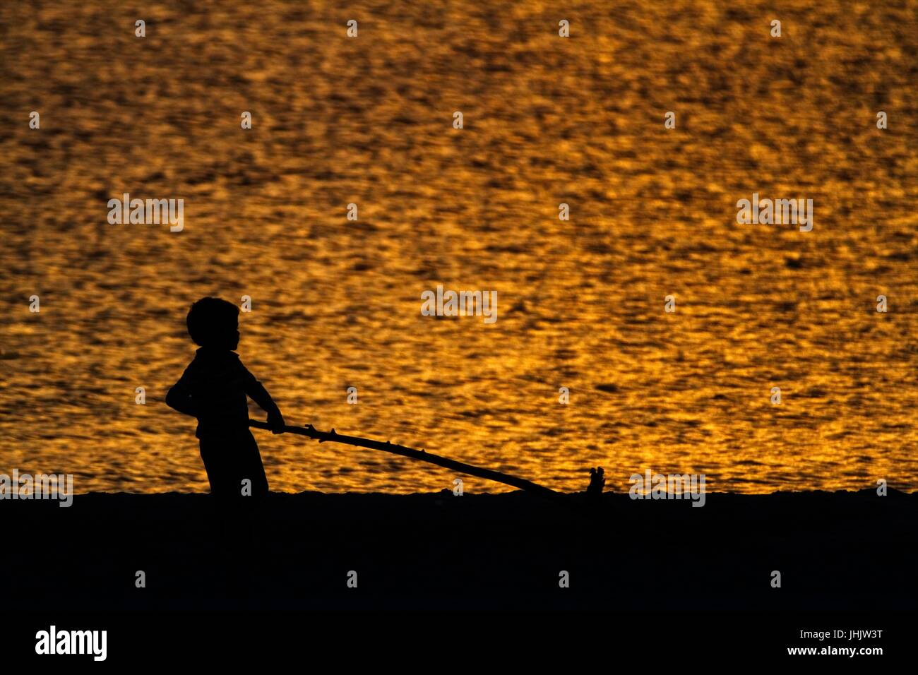 Coucher du soleil doré. Bord de mer. Silhouettes d'enfants. Banque D'Images