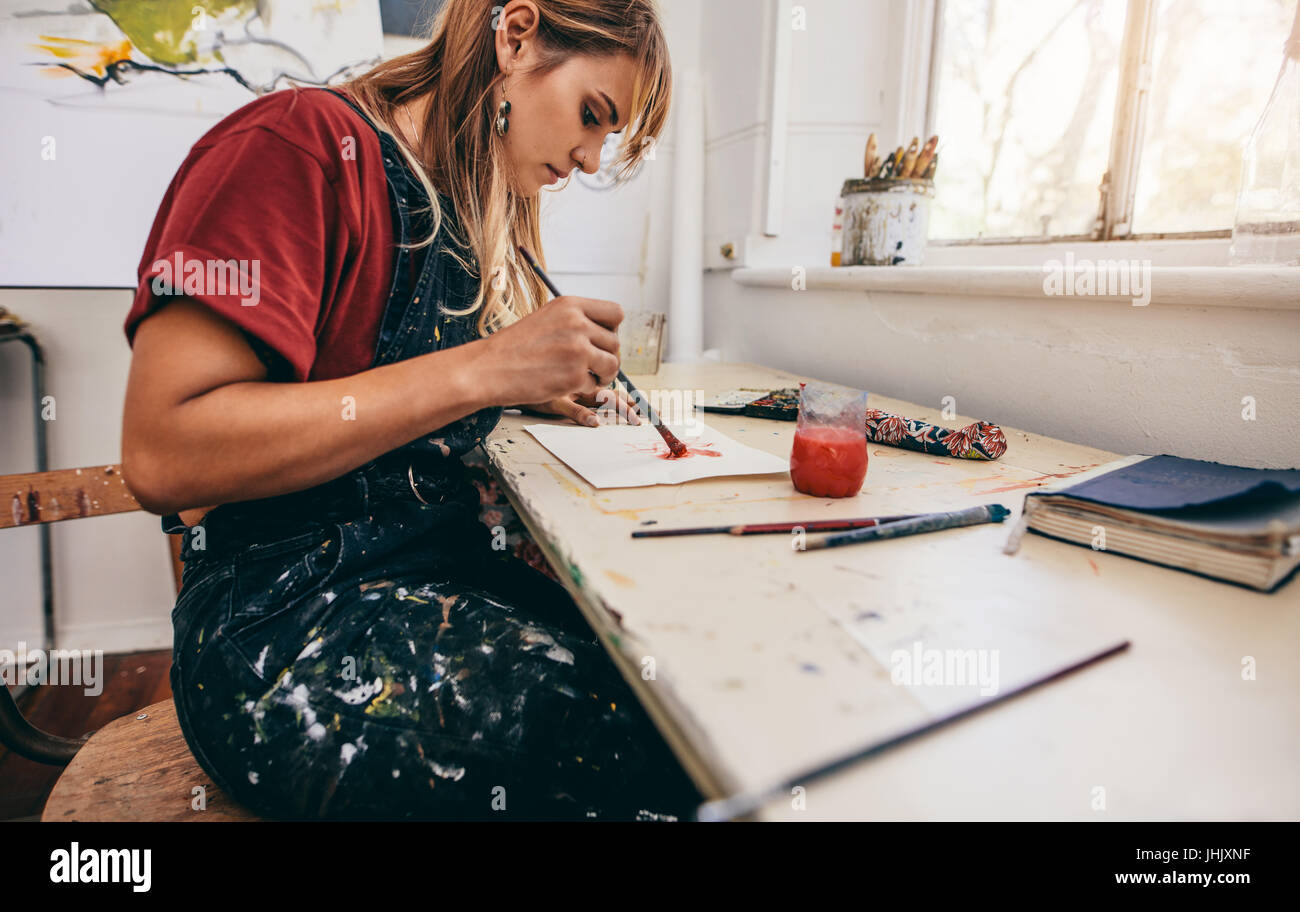 Vue latérale de l'artiste féminine belle photos de dessin dans son atelier. Jeune femme dans son atelier de peinture. Banque D'Images