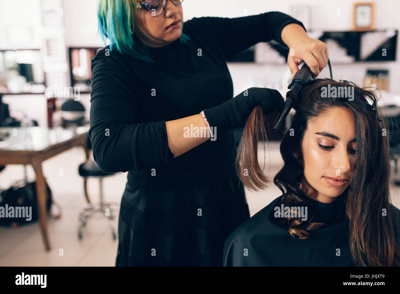Obtenir une femme à la Coiffure Salon de coiffure. Salon de beauté cheveux bouclés en tournant à l'aide d'un fer à friser les cheveux. Banque D'Images