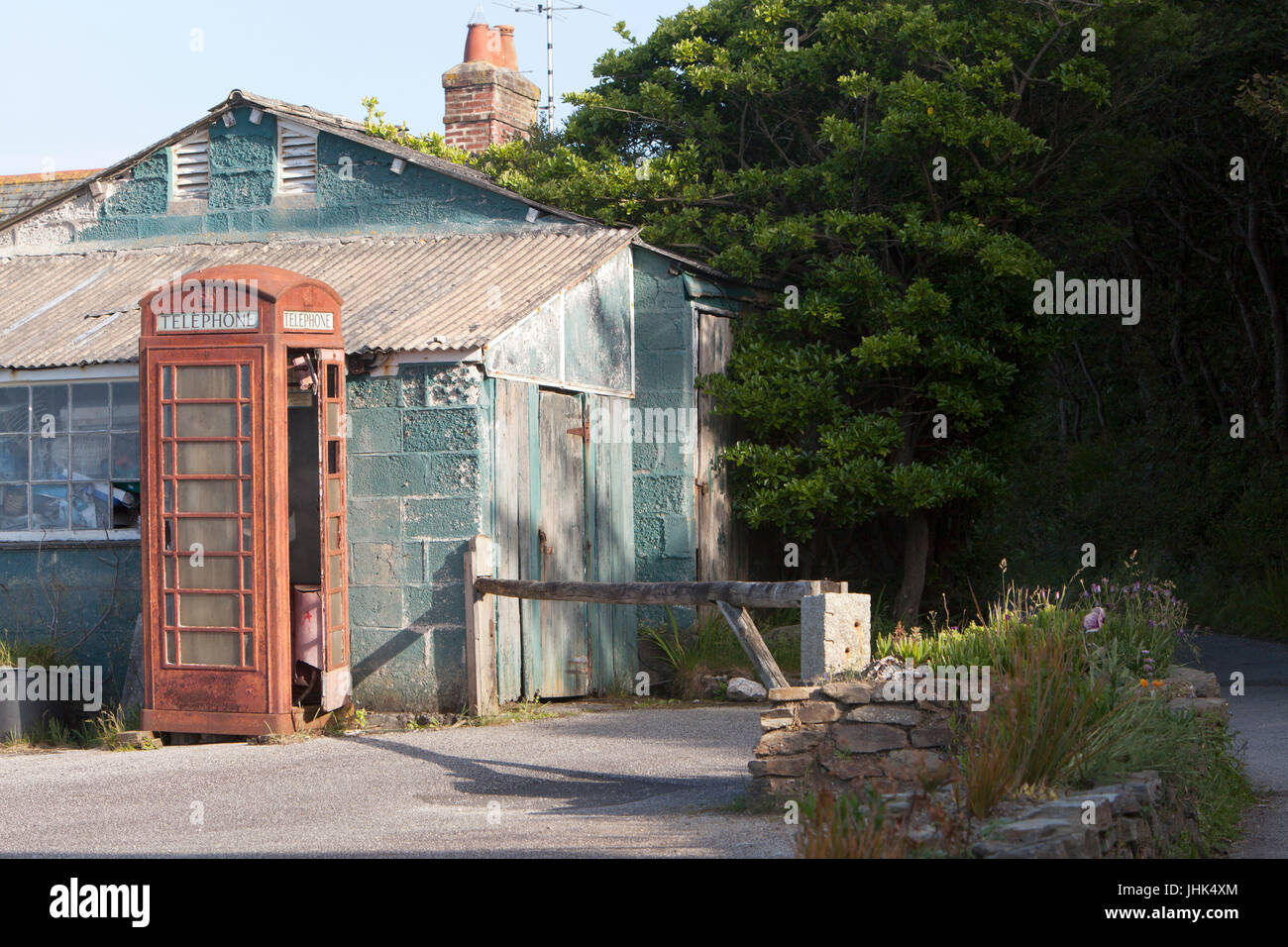 Une vieille et mal aimés abandonnés désaffectées boîte de téléphone rouge se tient à côté de l'abandon d'un immeuble délabré Banque D'Images