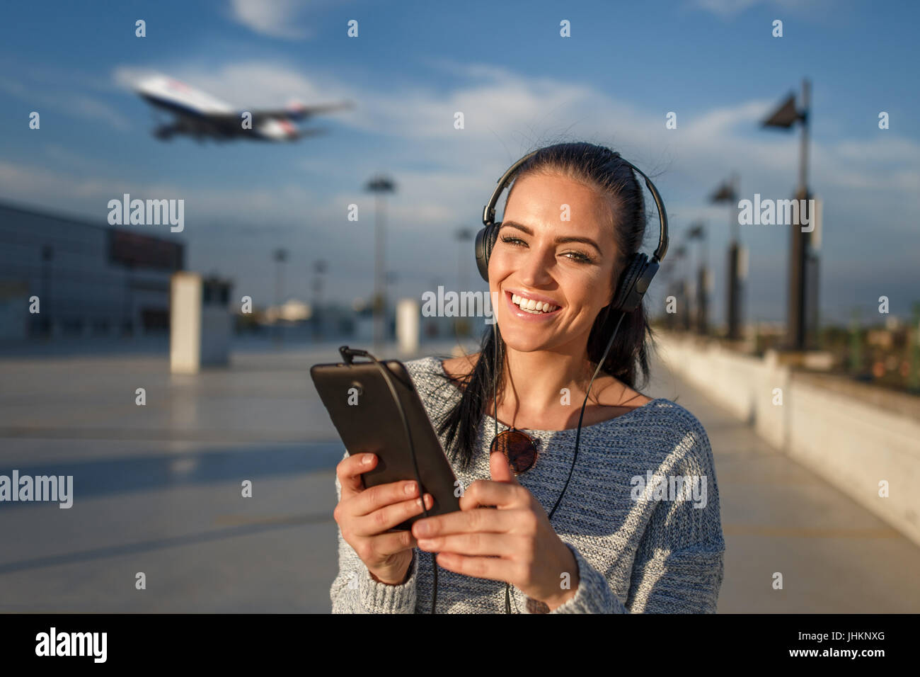 Happy young woman with headphones l'achat des billets d'air comprimé par Banque D'Images
