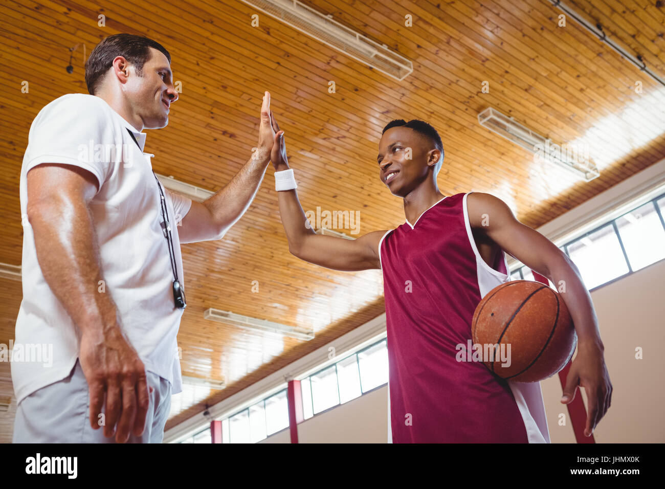 Low angle view of basketball player fiving haut avec l'entraîneur en position debout en cour Banque D'Images