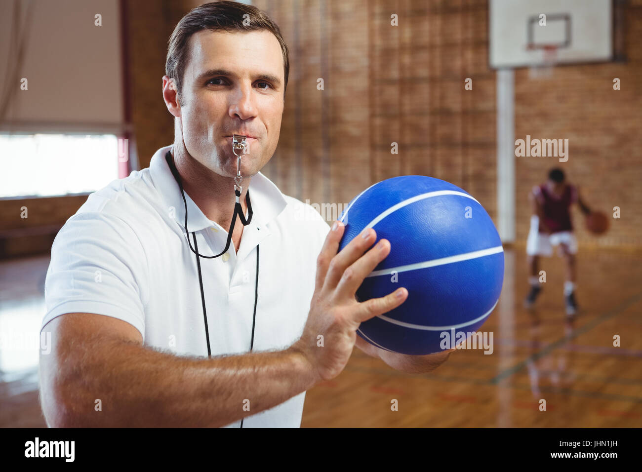 Portrait de coach sifflement tout en maintenant en cour de basket-ball Banque D'Images