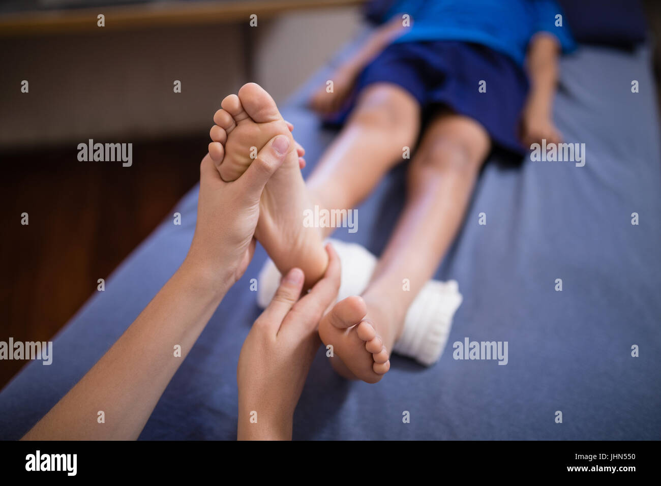 Portrait of boy lying on bed recevoir massage des pieds de thérapeute de sexe féminin à l'hôpital Banque D'Images