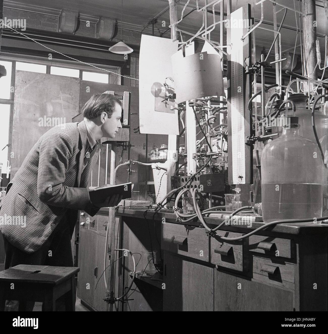 Années 1950, historiques, homme chercheur scientifique avec des études d'ordinateur portable les résultats de l'expérience et à l'aide de l'appareil de propagation de flamme dans le laboratoire de sciences à l'Université d'Oxford, Oxford, Angleterre, Royaume-Uni. Banque D'Images
