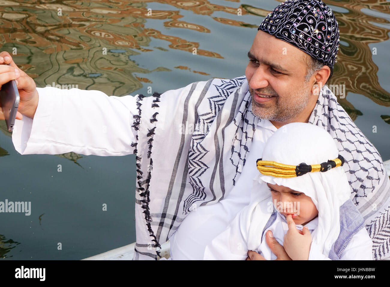 Un adorable enfant musulman arabe bien habillés de costumes costume sheik ou et en tenant avec selfies célèbre père profiter de l'occasion de l'Aïd Al Fitr Banque D'Images