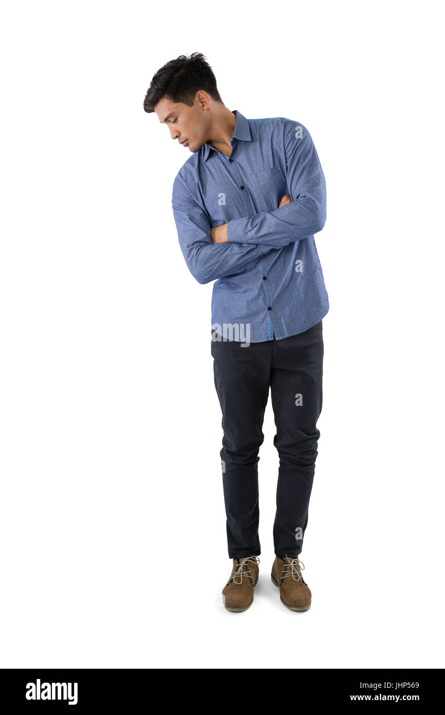 Toute la longueur de man tout en regardant vers le bas standing against white background Banque D'Images