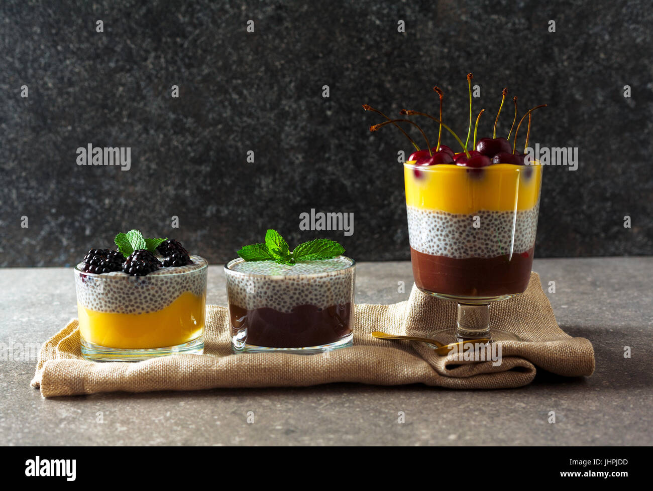 Desserts en couches de chocolat et vanille pudding et aussi de graines de chia avec des cerises mûres sur le dessus et des feuilles de menthe. Concept d'Eatin'Msain Banque D'Images