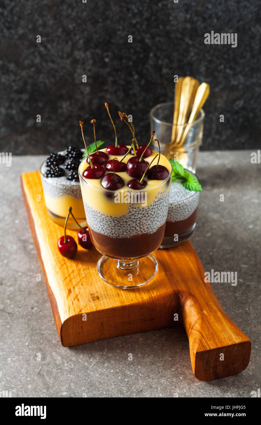 Desserts en couches de chocolat et vanille pudding et aussi de graines de chia avec des cerises mûres sur le dessus et des feuilles de menthe. Concept d'Eatin'Msain Banque D'Images