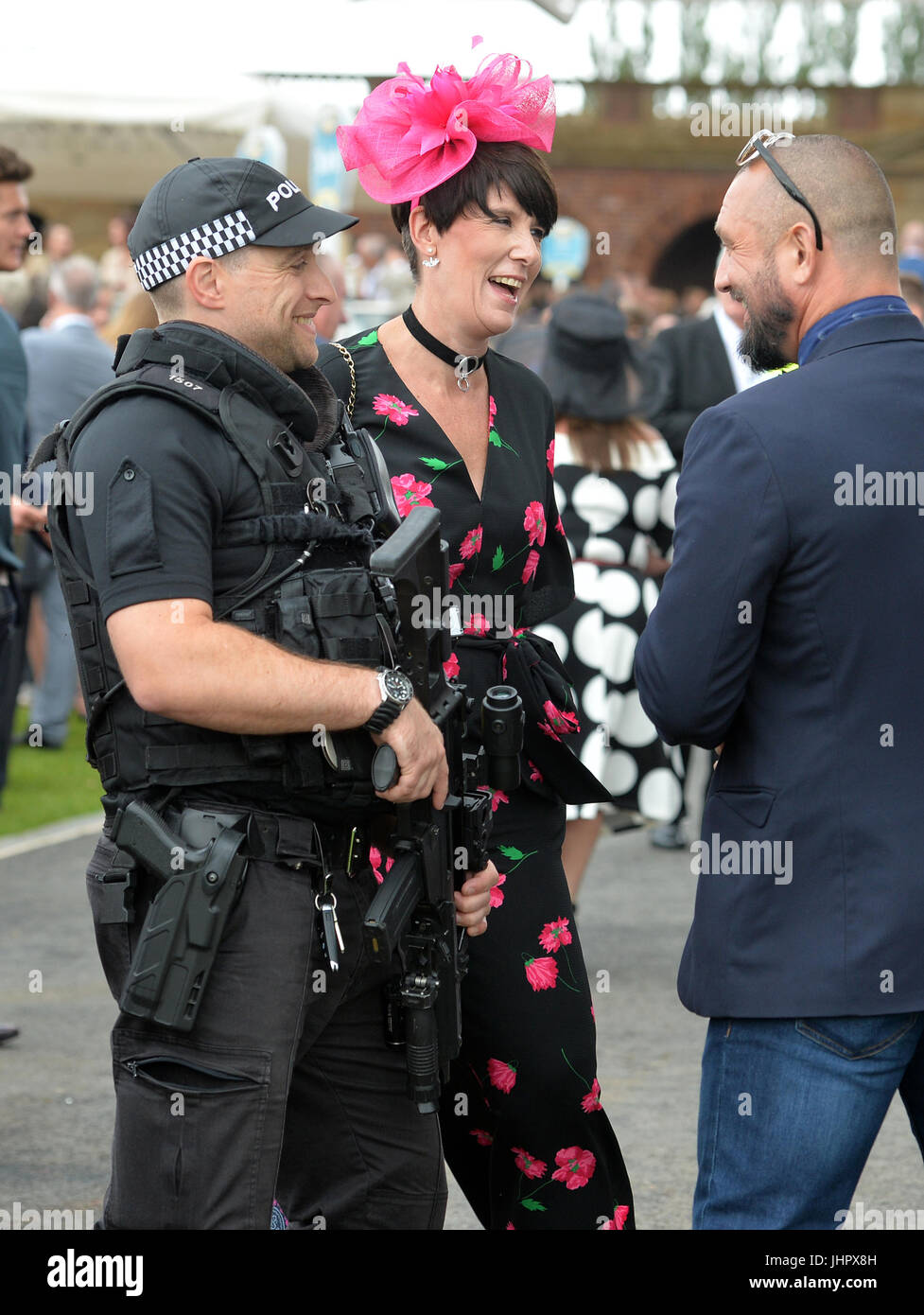 Chat Racegoers à un agent de police armé pendant la deuxième journée de la réunion de la Coupe John Smith à l'hippodrome de York. Banque D'Images