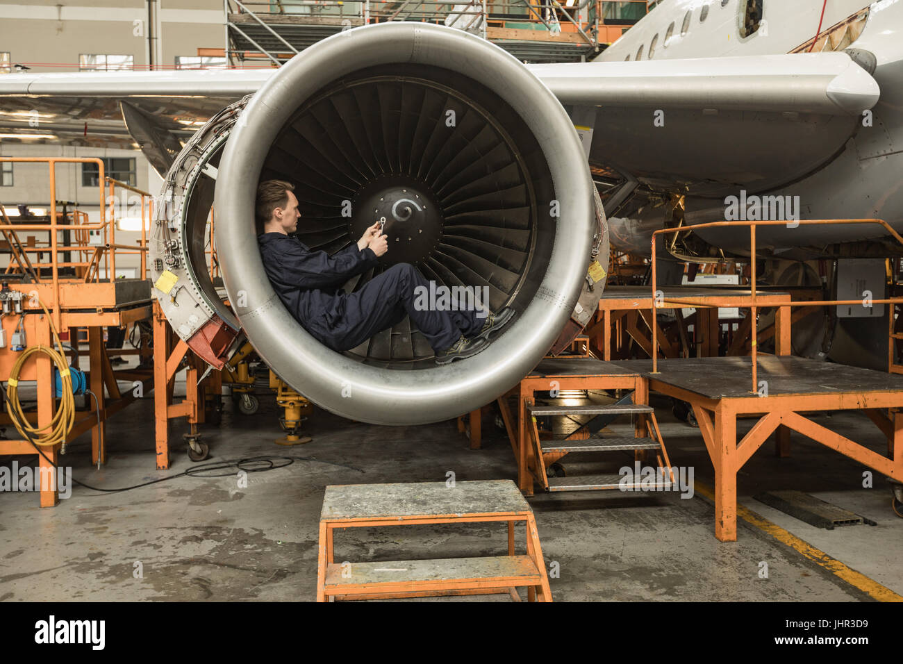 Homme technicien d'entretien d'aéronef de turbine de fixation de l'aéronef à l'installation de maintenance des compagnies aériennes Banque D'Images
