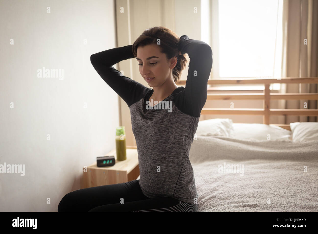 Jeune femme cheveux attacher en position assise sur le lit chez lui Photo  Stock - Alamy