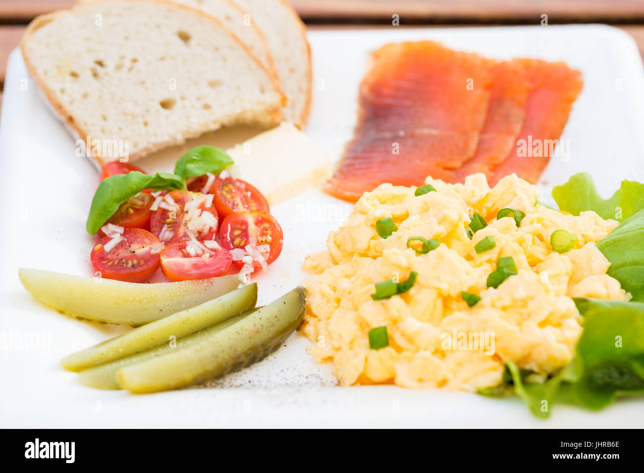 Set de petit-déjeuner, des œufs brouillés à la ciboulette, le poisson, le concombre, la tomate et le pain Banque D'Images
