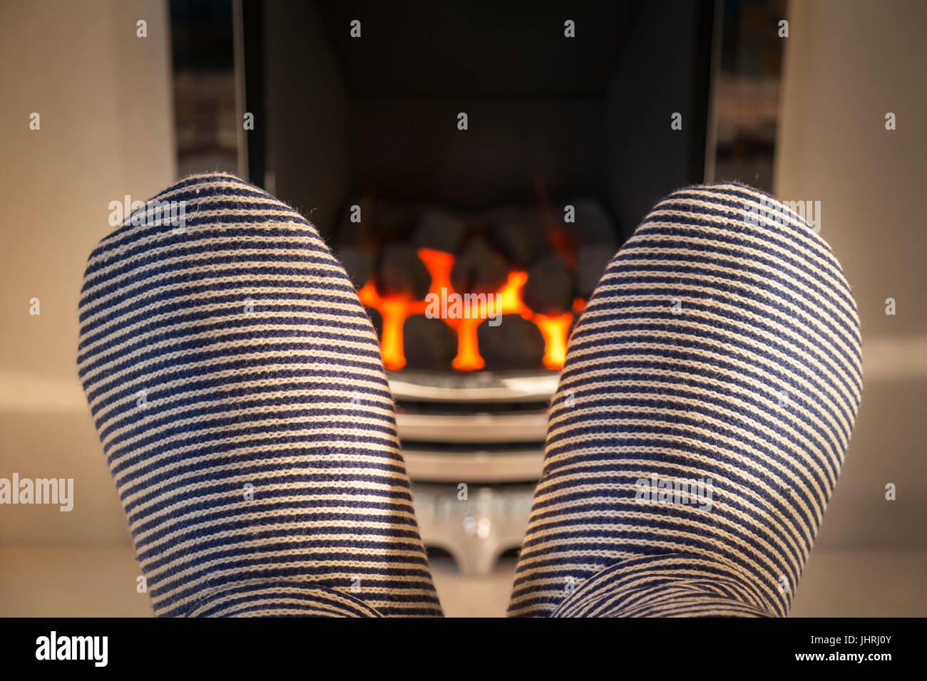 Pieds avec des chaussons épais d'être réchauffé en face d'un feu de gaz. Banque D'Images
