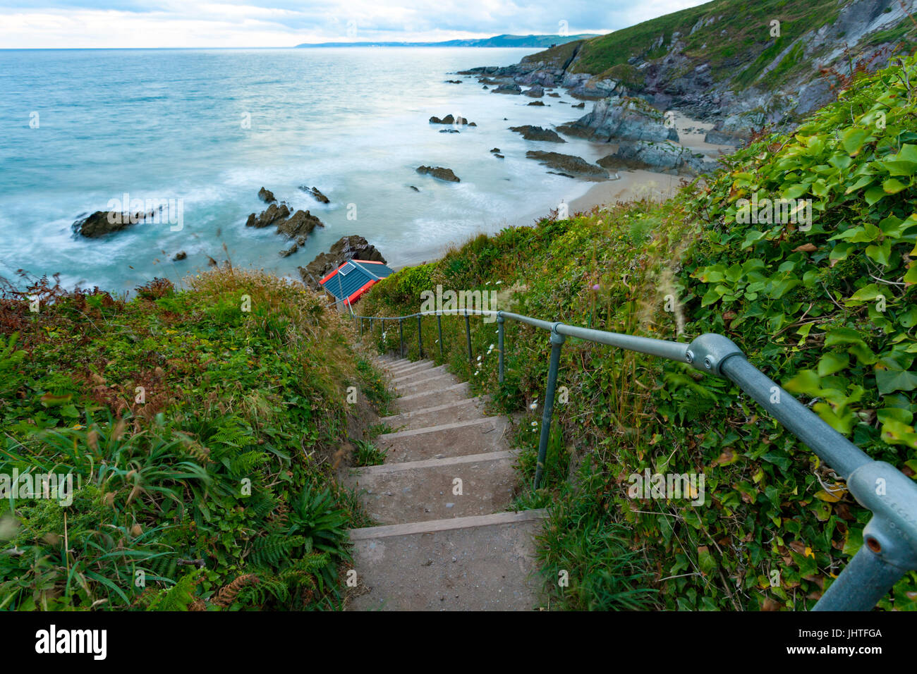 Étapes menant la drapeau bleu immaculé et populaire plage de Whitsand Bay à Freathy, Cornwall au crépuscule avec troubles de vagues se briser contre le rivage Banque D'Images