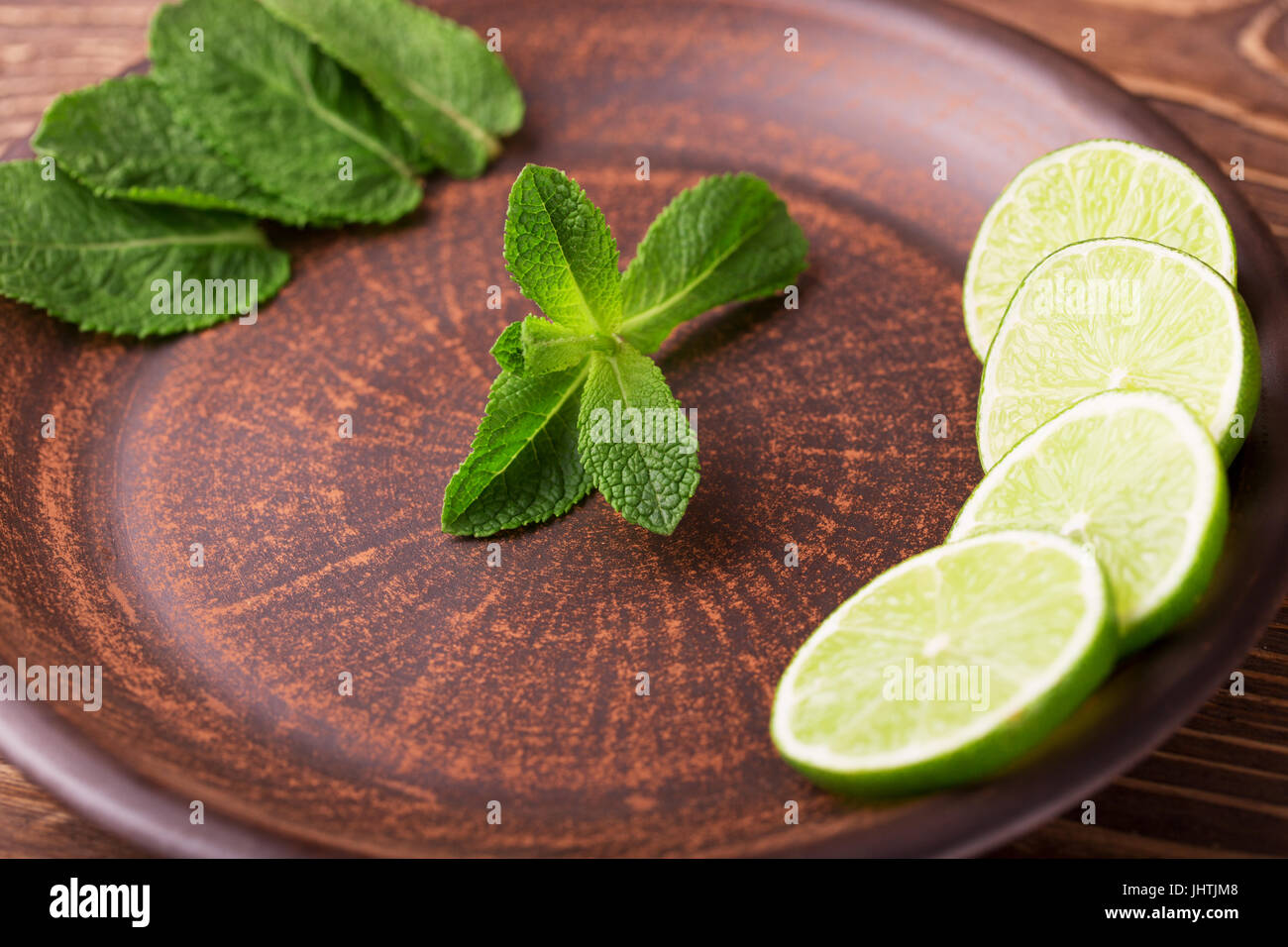 Tranches de lime et de feuilles de menthe sur une plaque sombre Banque D'Images