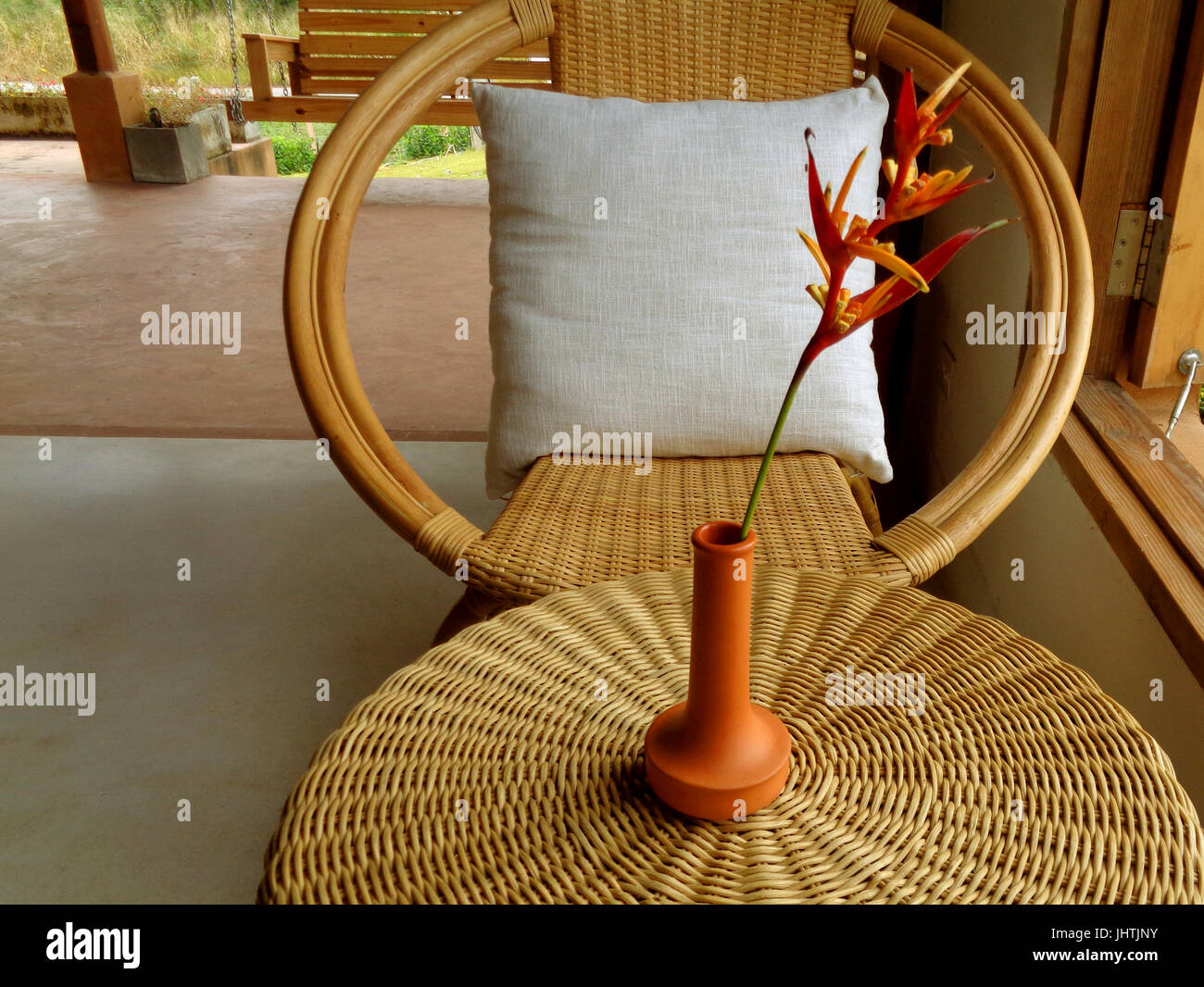 Espace détente avec canapé en rotin et table ronde avec les oiseaux du paradis fleur en vase en terre cuite Banque D'Images
