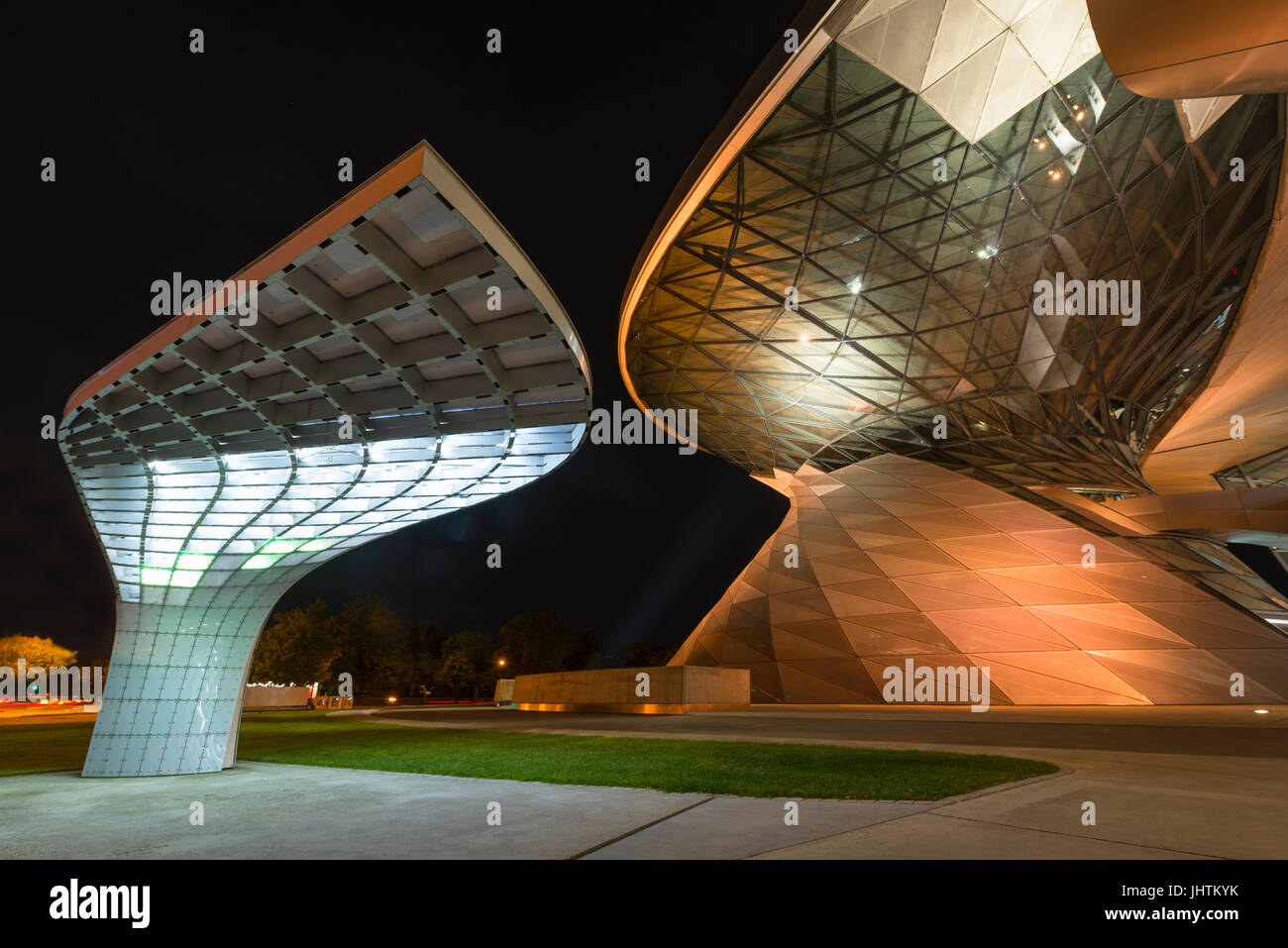 Architecture futuriste d'un chargeur électrique pour les voitures électriques à l'avant de la façade illuminée de la BMW Welt à Munich dans la nuit Banque D'Images