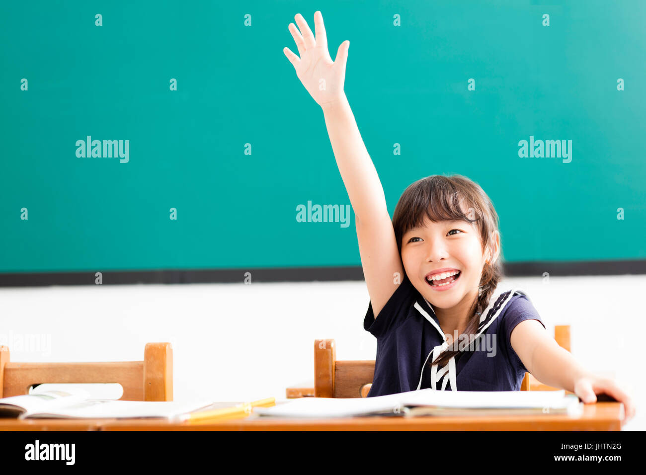 Happy little girl soulevées en classe les mains Banque D'Images