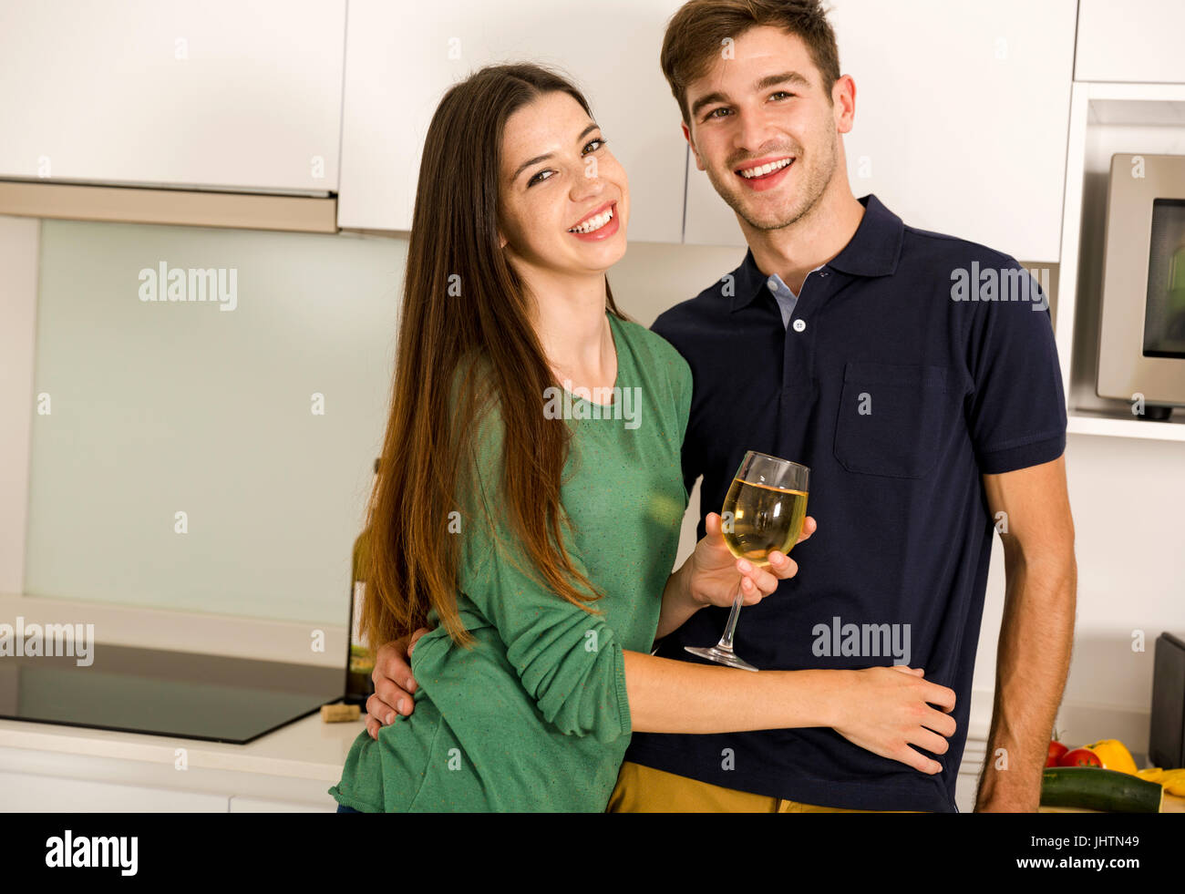 Jeune couple sur la cuisine prendre un verre de vin blanc Banque D'Images