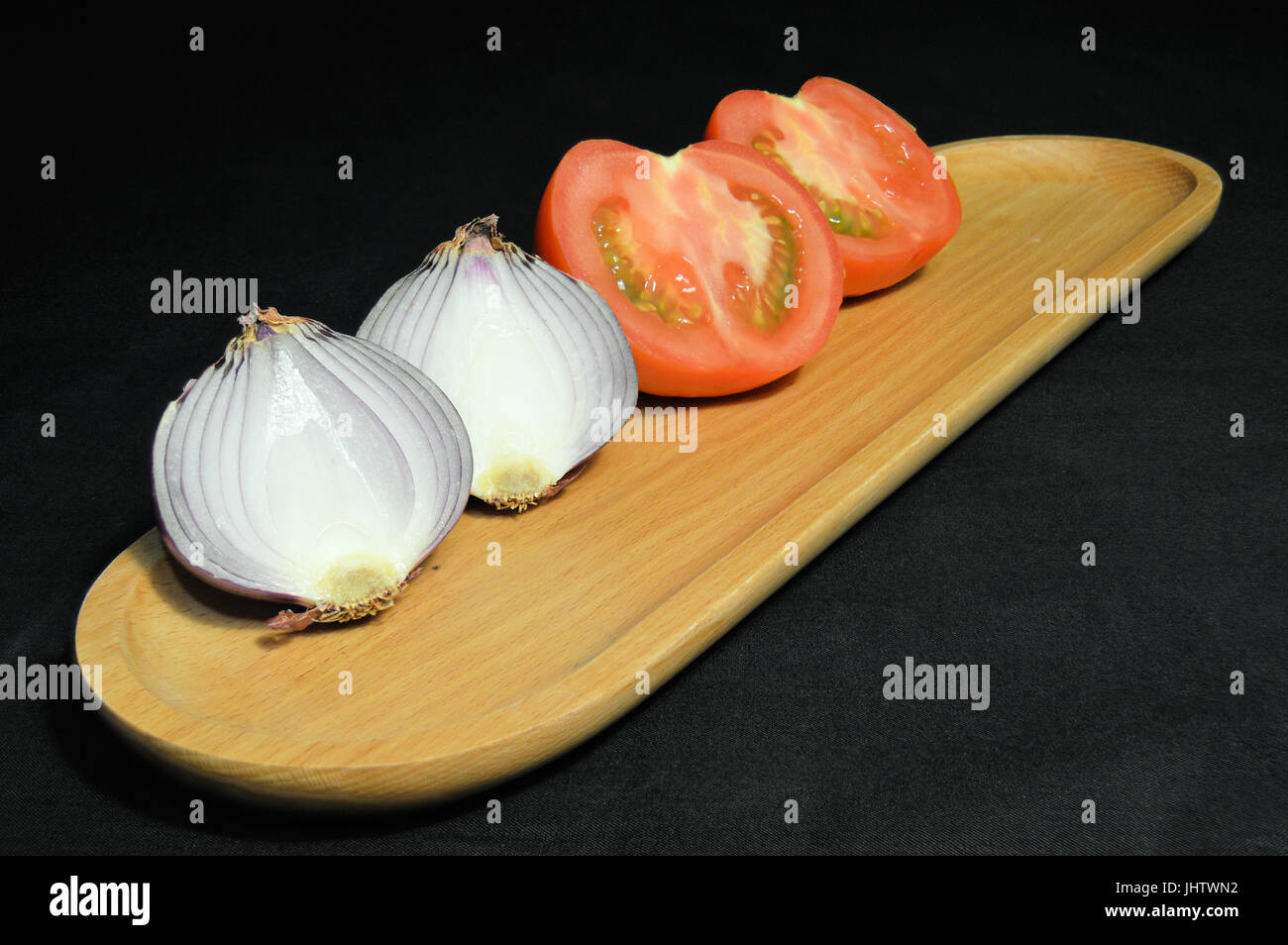 L'oignon et les tomates coupées en deux sur la plaque/plateau de service en bois Banque D'Images L'oignon et les tomates coupées en deux sur la plaque/plateau de service en bois Banque D'Images