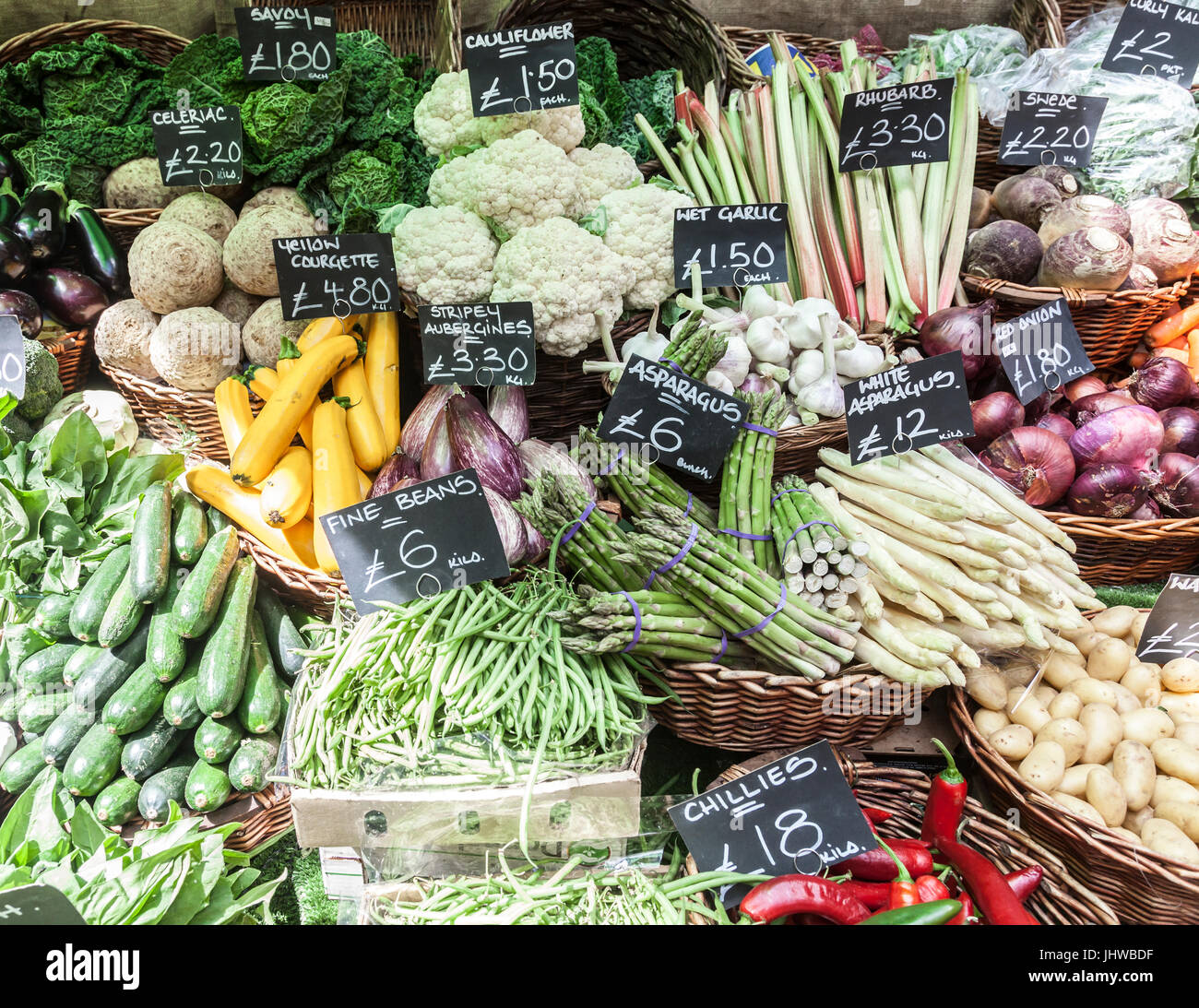 Kiosque de légumes à Borough Market, Southwark, Londres, en Angleterre. L'ail, les aubergines stripey humide, des haricots verts, asperges, choux, courgettes jaunes Banque D'Images