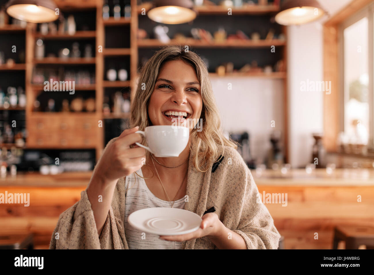 Portrait de belle jeune femme debout dans un café et de boire du café. Souriante jeune femme avoir du café dans un restaurant. Banque D'Images