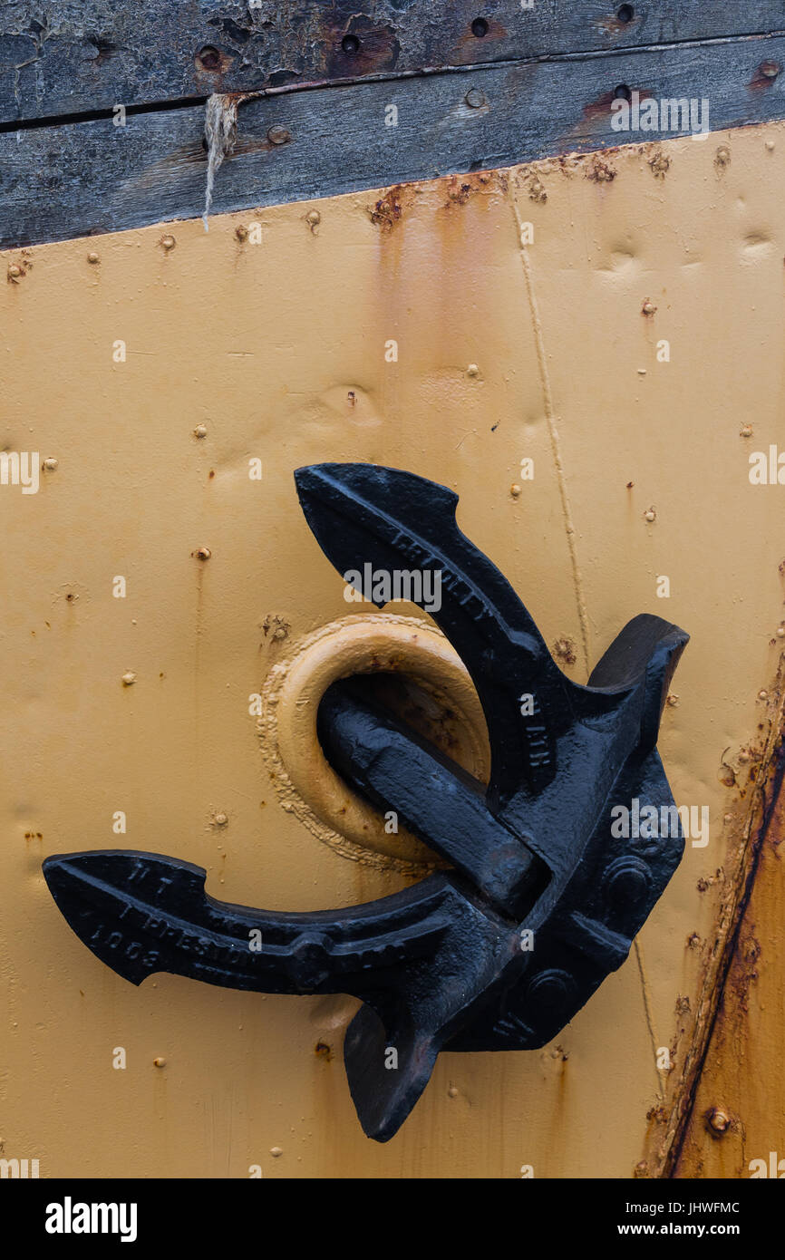 Ancre noire reposant contre une plaque de protection en métal sur la proue d'un bateau en bois Banque D'Images