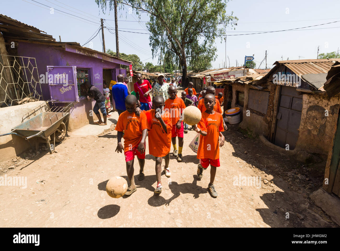 Les enfants de Kibera marche à travers les rues latérales avec le football après la formation, Nairobi, Kenya Banque D'Images