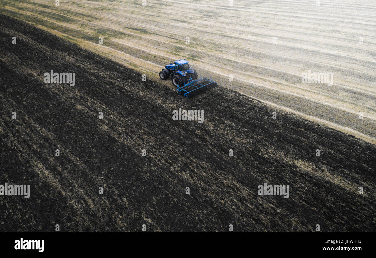 Cultiver du tracteur au champ du printemps, vue aérienne Banque D'Images