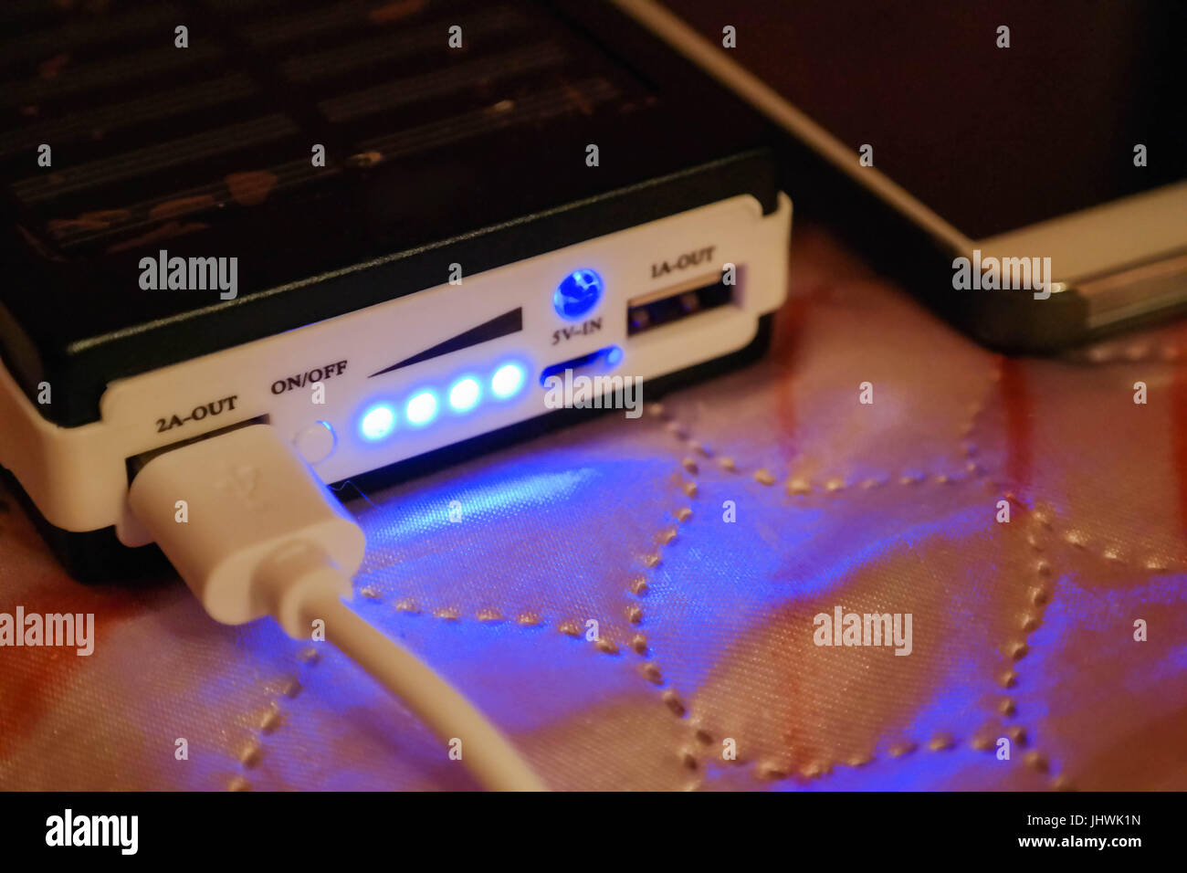 La charge d'un téléphone mobile en utilisant une banque d'alimentation. Premier plan rose. Voyants de charge bleu. Banque D'Images