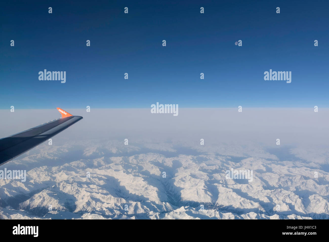 Voir d'Easy Jet airplane wing à partir de la fenêtre en survolant les Alpes, ciel bleu et la lune Banque D'Images