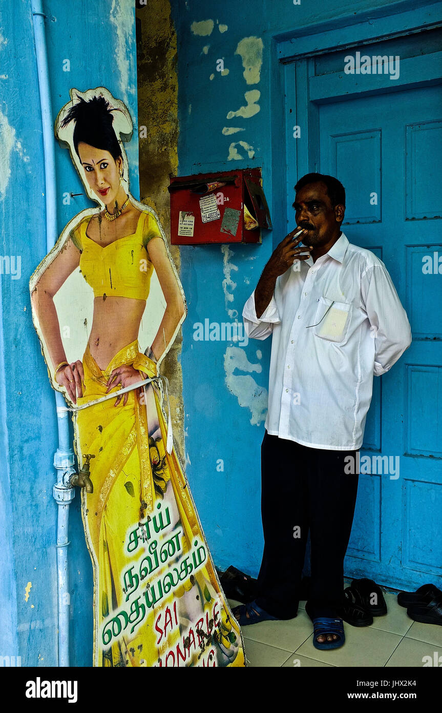 Un Indien regarde attentivement lors d'une découpe de carton d'une indienne tout en fumant une cigarette à l'extérieur d'une boutique à Georgetown, Penang, Malaisie Banque D'Images