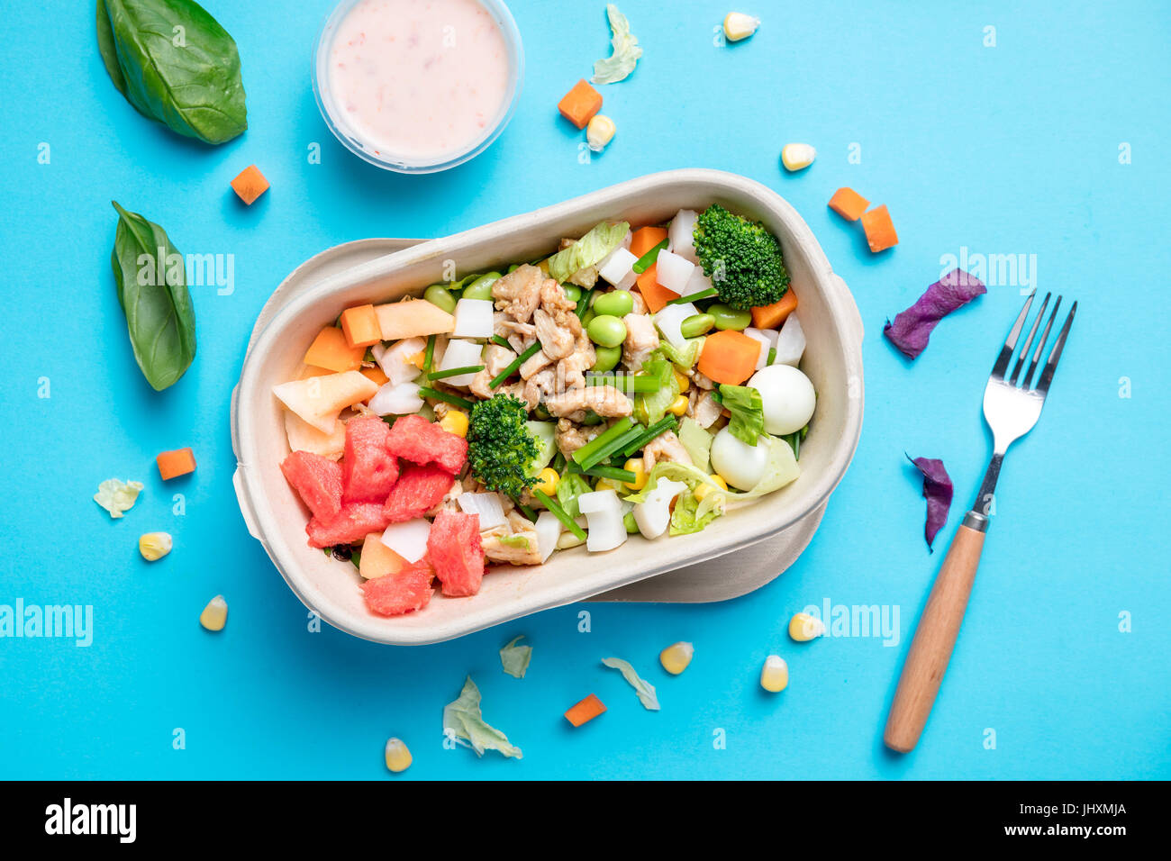 Un bol de salade de poulet sur le fond bleu dans une boîte à emporter. Banque D'Images