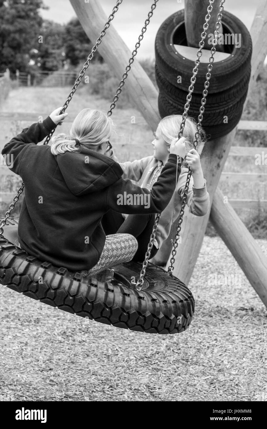 Enfants jouant sur un pneu en caoutchouc à l'aire de jeux Banque D'Images