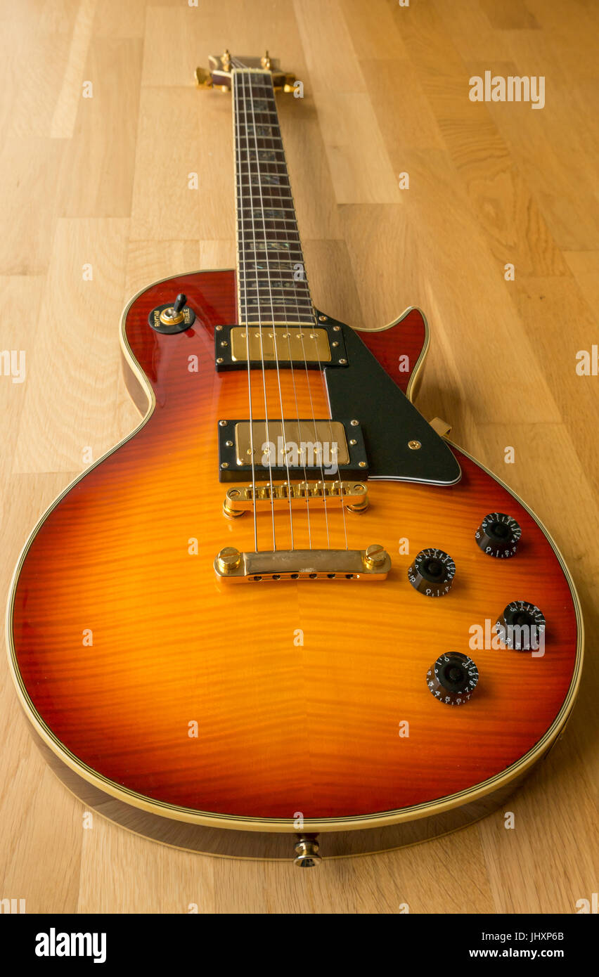 Les Paul Westfield Cherry guitare électrique, arrière-plan en bois clair avec contrôles de volume et tonalité et sélecteur de ramassage Banque D'Images